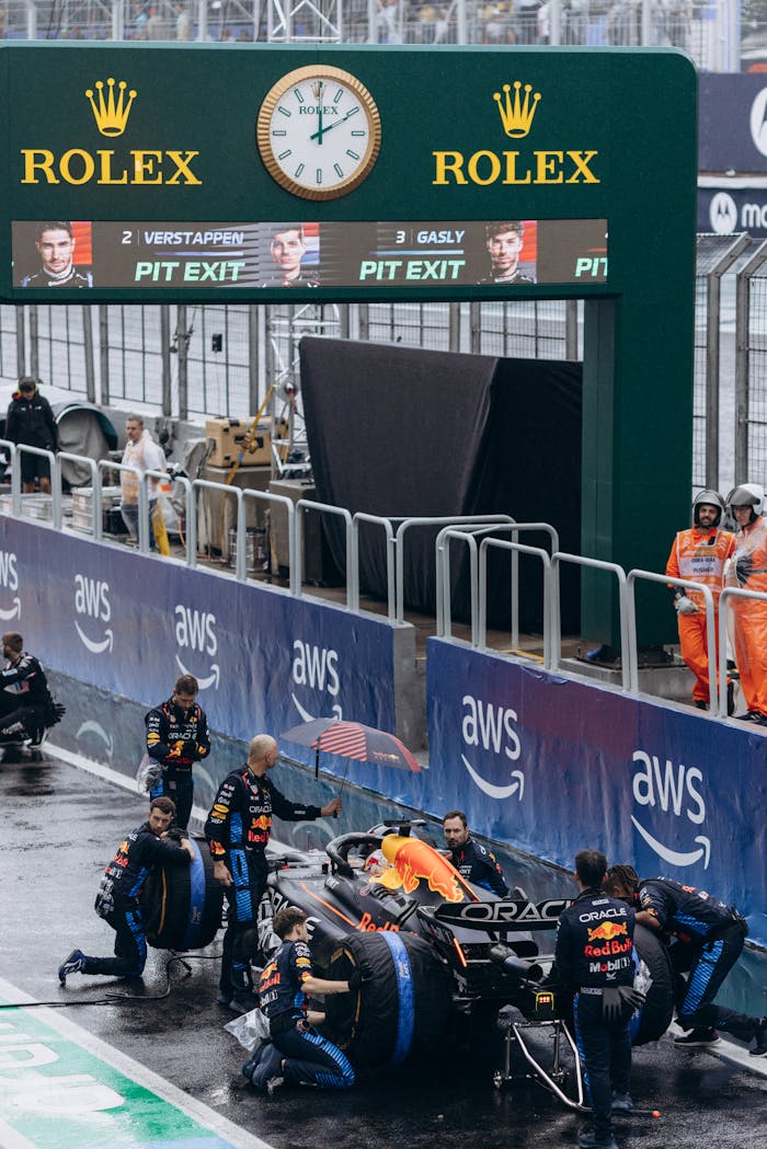 Formula 1 team performs swift pit stop in rainy conditions, showcasing teamwork.